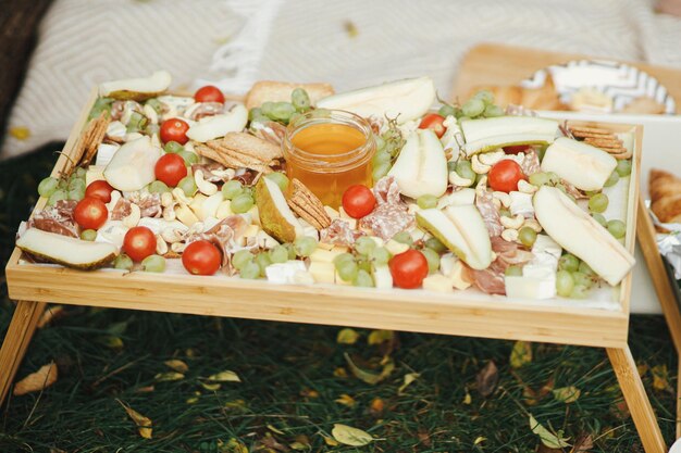 Charcuterie bord met kaas prosciutto peren honing druiven noten Antipasto op een zonnige picknick