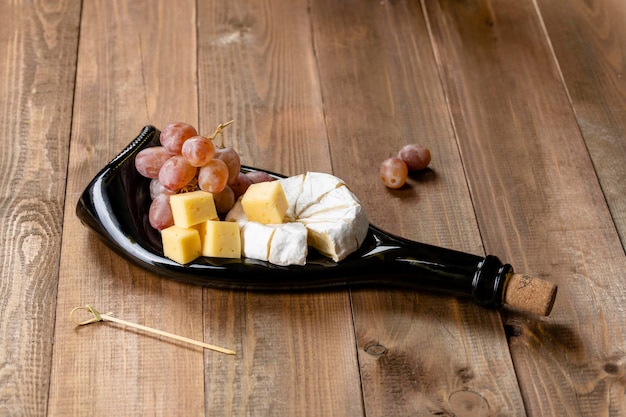 Charcuterieplank snackplank kaas en druiven op een stijlvolle glazen plank van gesmolten glazen fles