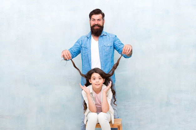 In charge of daughters hairstyle. Father and daughter having fun. Child and dad best friends. Parenthood challenges. Lovely father and cute kid. Happy to be father. Hairdresser deal with long hair.