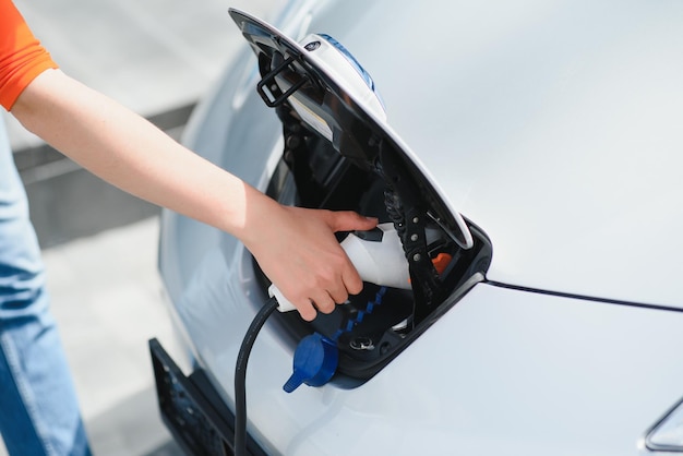 Charging car Young woman in casual clothes with her electromobile outdoors at daytime