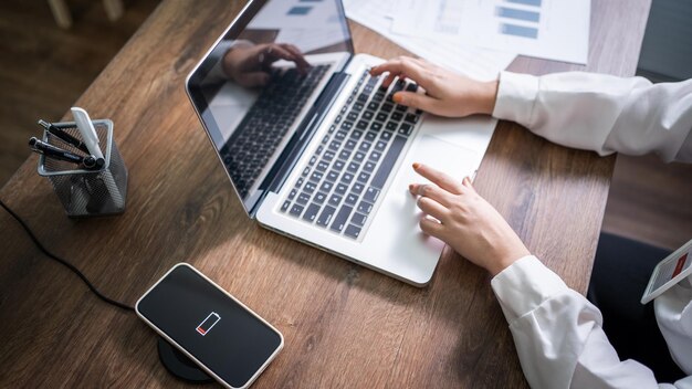 Charging mobile phone battery with wireless charging device in the table Smartphone charging on a charging pad Mobile phone near wireless charger Modern lifestyle technology concept