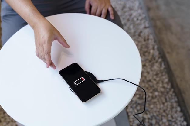 Photo charging mobile phone battery with wireless charging device in the table smartphone charging on a charging pad mobile phone near wireless charger modern lifestyle technology concept