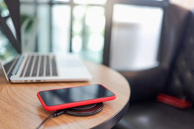 Charging mobile phone battery with wireless device in the table Smartphone charging on a charging pad Mobile phone near wireless charger