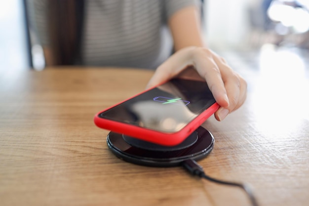 Charging mobile phone battery with wireless device in the table Smartphone charging on a charging pad Mobile phone near wireless charger