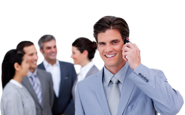 Charismatic businessman on phone standing apart from his team