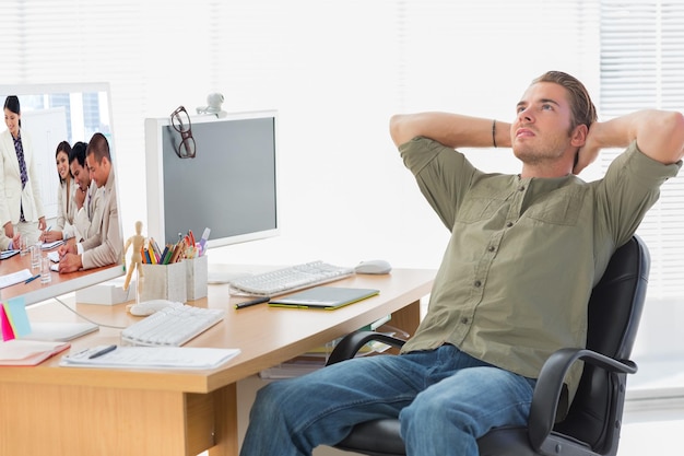 Photo charismatic businesswoman doing a presentation against handsome designer leaning back at his desk