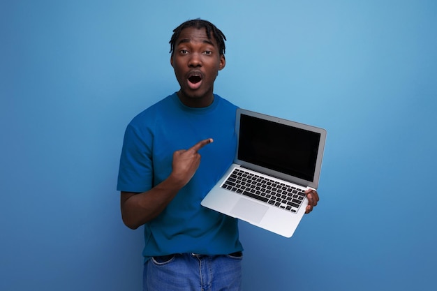 Charismatic consultant demonstrates laptop screen on studio background with mockup and copy space