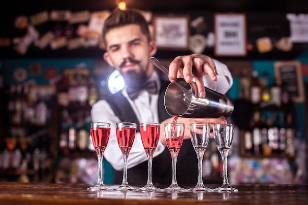 Photo charismatic female bartender mixes a cocktail while standing near the bar counter in pub