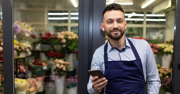 charismatic male florist next to the refrigerator with bouquets.