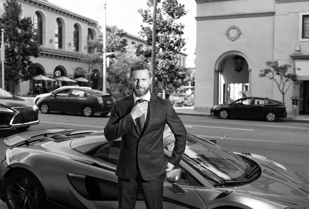 Charismatic unshaven boss stand by luxury automobile blue color outdoor luxury life