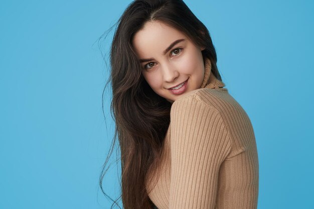 Photo charismatic young lady smiling at camera in blue studio