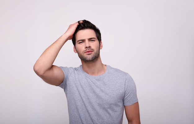 Charismatic young man looking at camera while standing against gray.