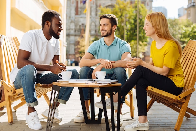 Photo charismatic young people discussing and having fun at cafe