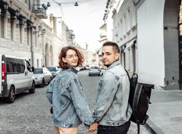 Charismatisch modern paar verliefde toeristen in spijkerjacks slenteren langs de stedelijke straatxA