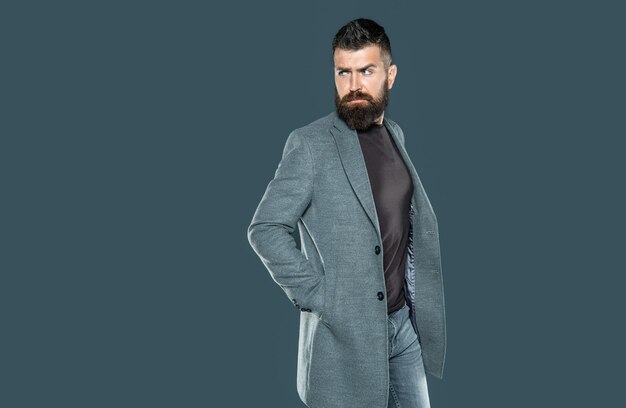 Charismatische volwassen man met baard draagt casual op grijze achtergrond