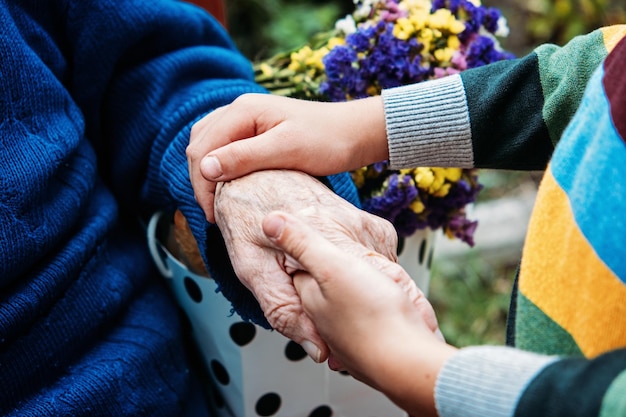 高齢者のための慈善団体高齢者の高齢者の手を握っている若い手は高齢者を支援します