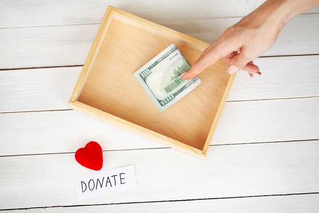 Photo charity fundraiser box with dollars on white wooden background