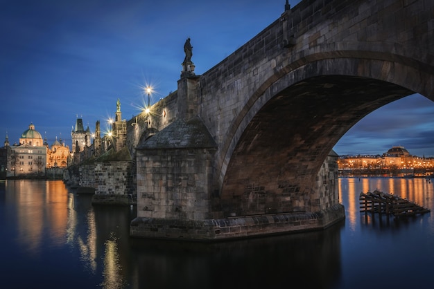 charles bridge over vltava with national theatre under the arch at night in prague