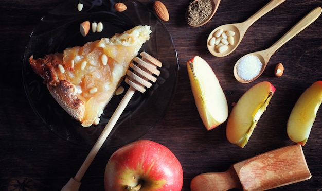 Charlotte met appels en noten. Bereiding van appel bakken met noten en honing. Dessert gebakken goederen van appels en noten met honing op een houten tafel.