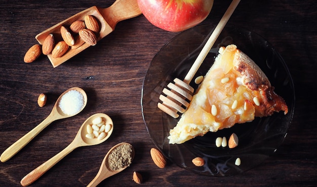 Charlotte with apples and nuts. Preparation of apple baking with nuts and honey. Dessert baked goods from apples and nuts with honey on a wooden table.