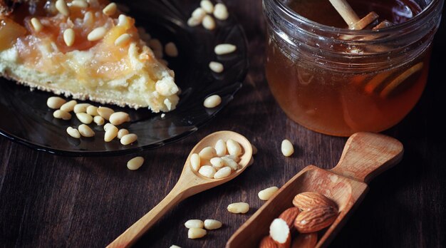 사과와 견과류를 곁들인 샬롯. 견과류와 꿀을 곁들인 사과 베이킹 준비. 나무 테이블에 꿀을 곁들인 사과와 견과류로 구운 디저트를 맛보세요.
