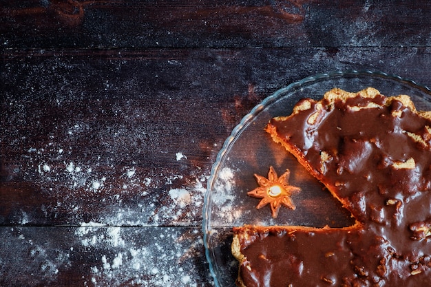 Charlotte with chocolate glaze on wooden table with burning candle