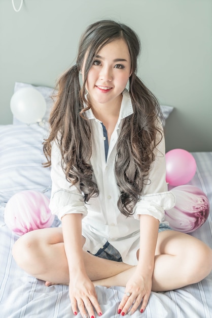 Charmant Aziatisch vrouw het glimlachen gezicht die op het bed liggen