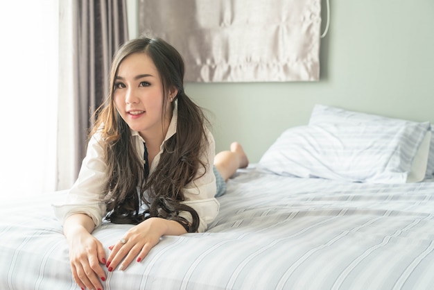 Charmant Aziatisch vrouw het glimlachen gezicht die op het bed liggen