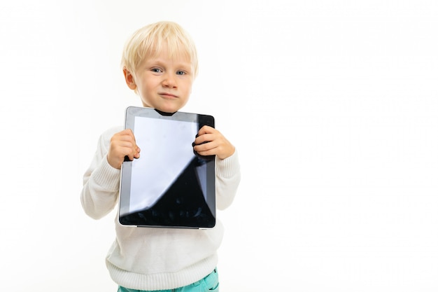charmant blond kind met een tablet op een witte muur