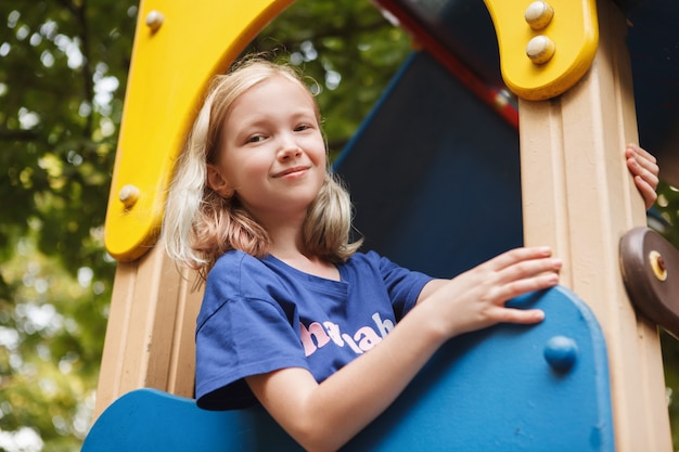 Charmant jong meisje dat lacht terwijl ze plezier heeft op de kinderspeelplaats