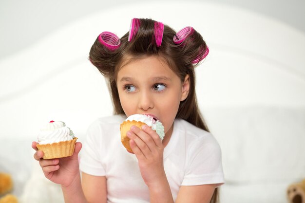 Charmant jong meisje met cupcake in elke hand.