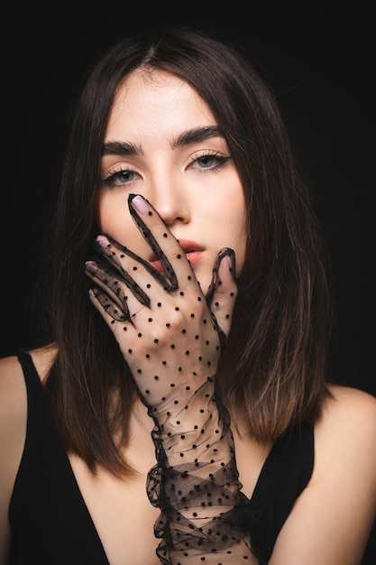Charmant jong meisje op een zwarte achtergrond Modieus portret van een meisje in transparante handschoenen
