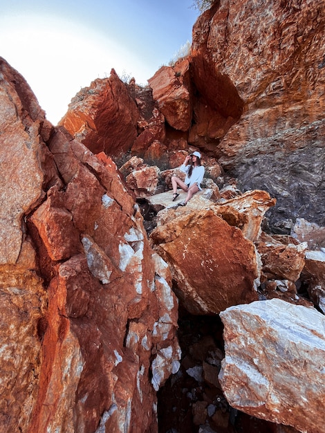 Foto charmant jong meisje zit in de rotsen in stenen canyon