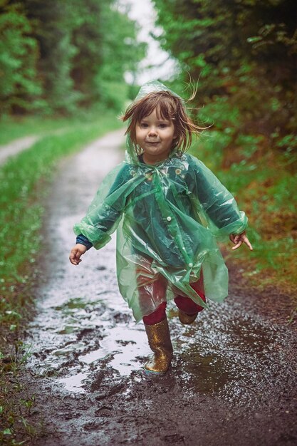 Charmant kind in een regenjas in het avondbos in Denemarken