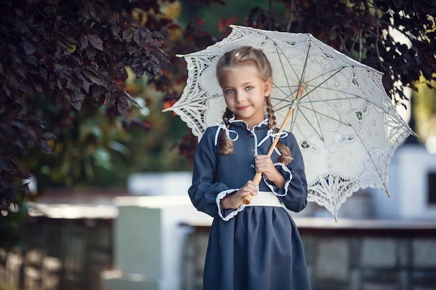 Charmant meisje in schooluniform loopt in de ochtendstad. Mooi jong schoolmeisje vóór lessen