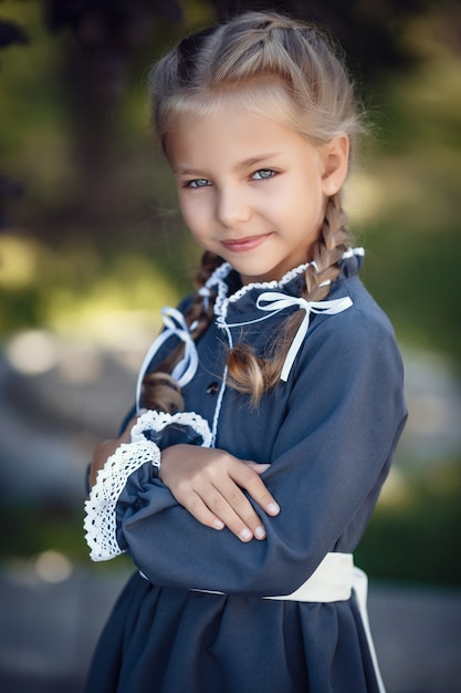 Charmant meisje in schooluniform loopt in de ochtendstad. Mooi jong schoolmeisje vóór lessen