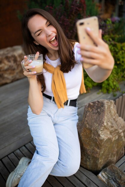 Charmant meisje maakt een selfie aan de telefoon zittend in een zomer groen park.