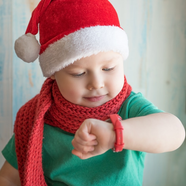 Charmante baby in een kerstmuts om de tijd te zien