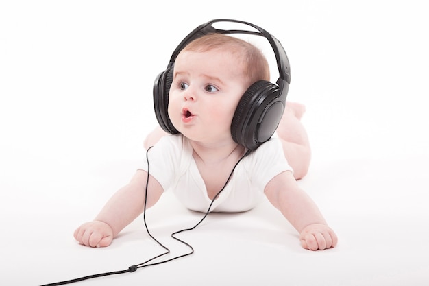 charmante baby op een wit met koptelefoon luisteren naar muziek
