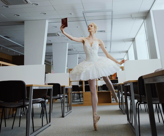 Charmante ballerina ging naar de bibliotheek om tijdens een pauze een nieuw boek te kiezen om je stretching en flexibiliteit te laten zien