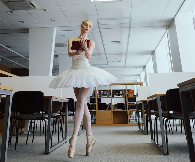 Charmante ballerina ging naar de bibliotheek om tijdens een pauze een nieuw boek te kiezen om je stretching en flexibiliteit te laten zien