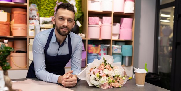 Charmante bloemist achter de toonbank van een bloemenwinkel naast een luxe boeket bloemen