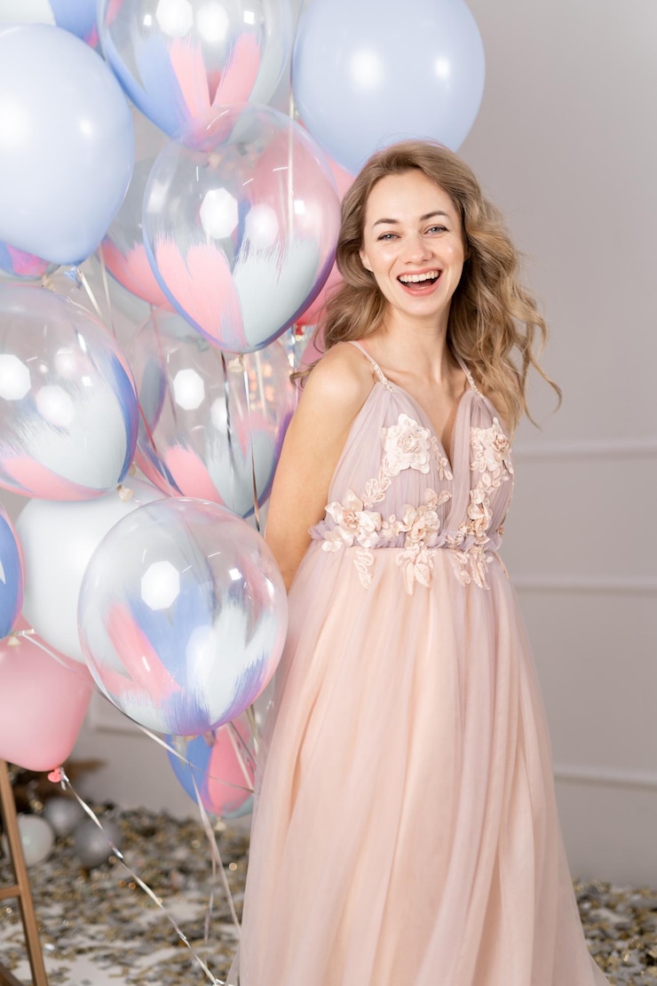 Foto charmante blonde vrouw in een stijlvolle jurk met een hoop verjaardagsballonnen over roze studio achtergrond kopieer ruimte feesttijd dame plezier viering genieten