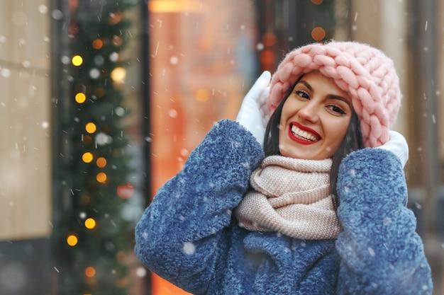 Charmante brunette vrouw in jas wandelen in de stad bij sneeuwweer. lege ruimte
