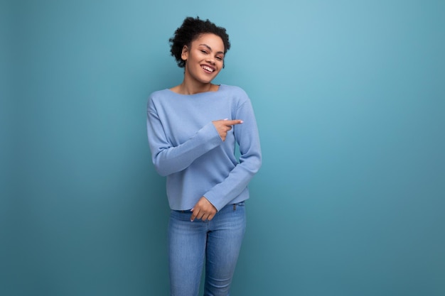 Charmante brunette vrouw met afro krullen in stijlvolle casual kleding geïsoleerd met studio achtergrond