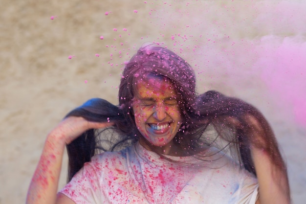 Charmante brunette vrouw met lang haar spelen met roze droog Holi-poeder in de woestijn