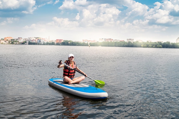 Charmante glimlachende vrouw rijdt op een sup paddleboard rond de actieve levensstijl, sport en gezondheid van het stadsmeer