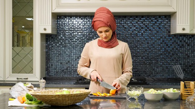 Charmante islamvrouw in hijab maakt speciale fruitsalade en kookt zelfgemaakte maaltijd voor familieclose-up