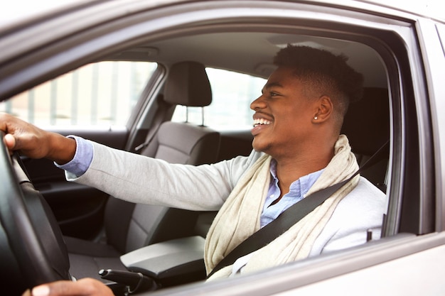 Charmante jonge Afro-Amerikaanse man die een auto rijdt in de stad.