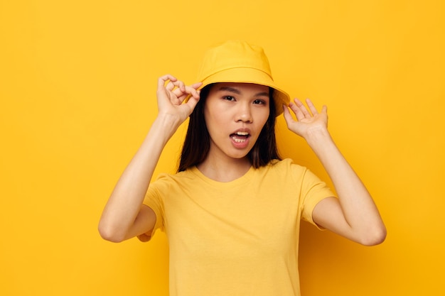 Charmante jonge Aziatische vrouw in een gele t-shirt en hoed die emoties stelt Ongewijzigde levensstijl